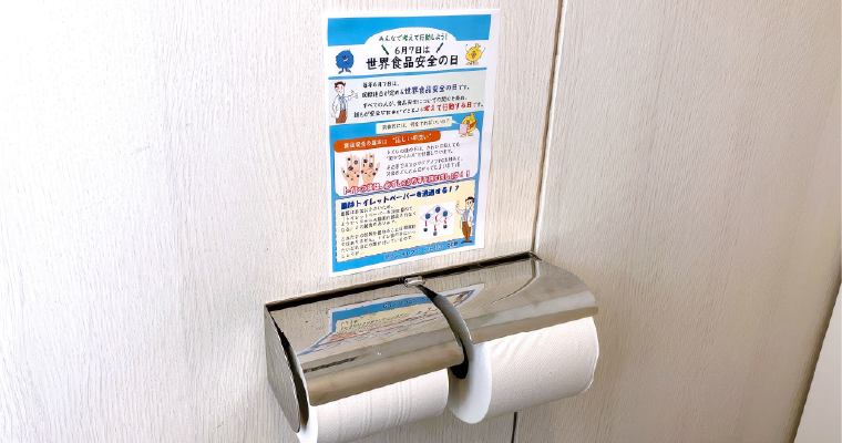 トイレ内の壁に掲示された、世界食品安全の日に関する社内向け啓発ポスター周辺の様子のイメージ